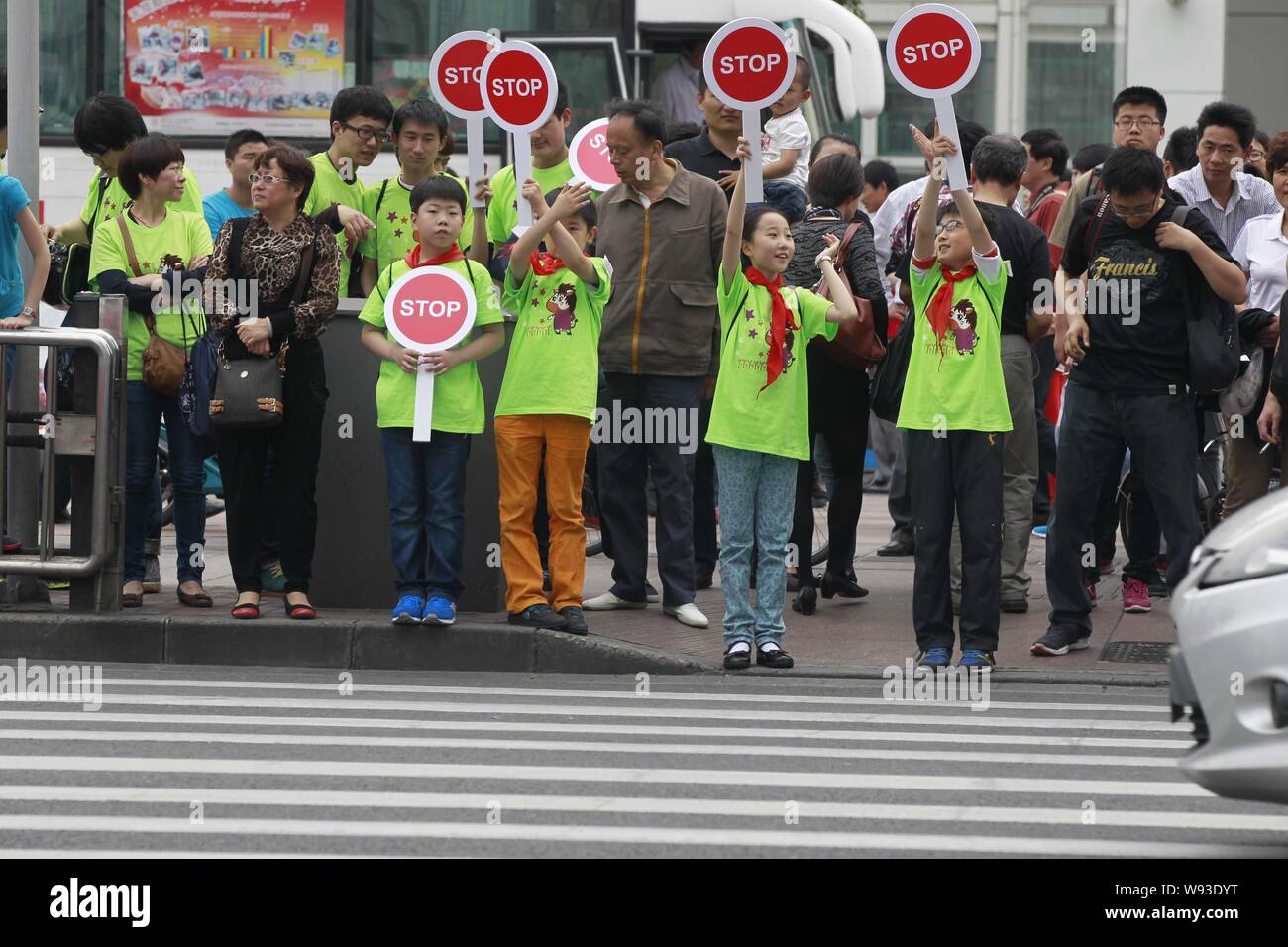 Chinesischen Probanden halten Stoppschilder gegen jaywalking an einem roten Licht auf einer Straße in Shanghai, China, 2. Juni 2013. Chinesische Beamte sind Risse tun Stockfoto