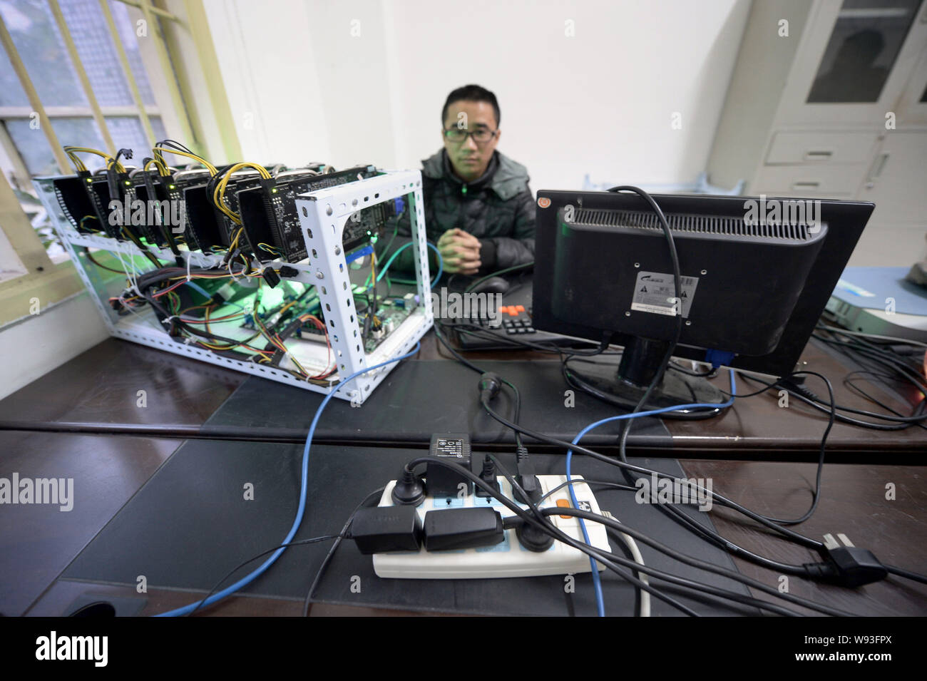 Ein Mann sitzt neben einer Bitcoin Mining Maschine im Büro des Chinesischen Bitcoin  Miner Feng Yupeng in Chongqing, China, 6. Dezember 2013. Feng Yupeng, ein  Stockfotografie - Alamy