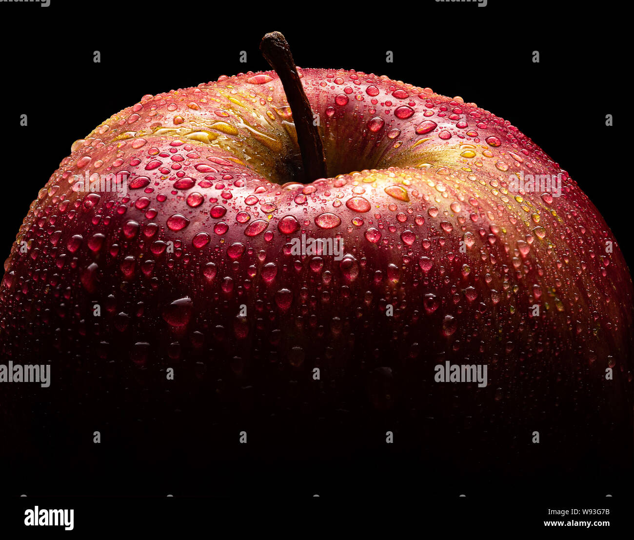 Schönen roten Apfel auf schwarzem Hintergrund closeup Makro mit vielen Wassertropfen Stockfoto