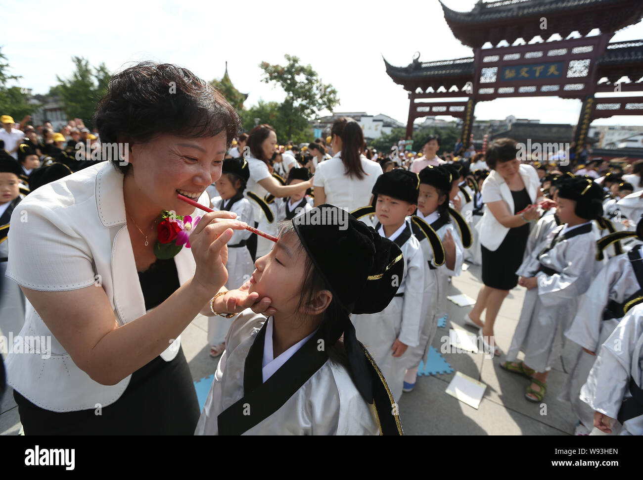 Ein Lehrer der Nanjing Konfuzius Tempel Grundschule zeichnet einen roten Punkt auf die Stirn eines ersten Schüler, die aufgerufen wird, Öffnen der Weisheit Auge Stockfoto