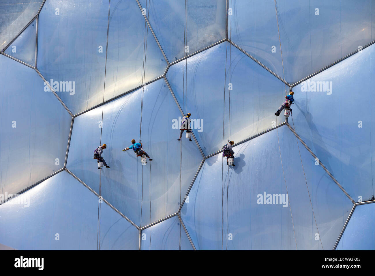 Chinesische Arbeiter sind in der Luft, als sie die Fassade des National Aquatics Center sind die Reinigung ausgesetzt ist, auch als Water Cube, Peking, Ch bekannt Stockfoto