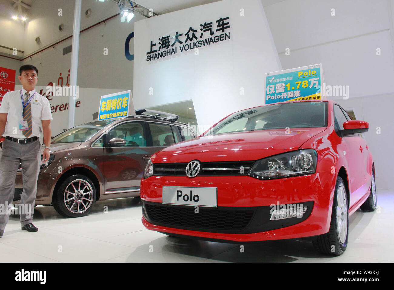 Ein chinesischer Mitarbeiter steht neben einem Polo Auto von Shanghai Volkswagen in einem Automobil Ausstellung in Haikou, South China Hainan Provinz, 5 Septemb Stockfoto