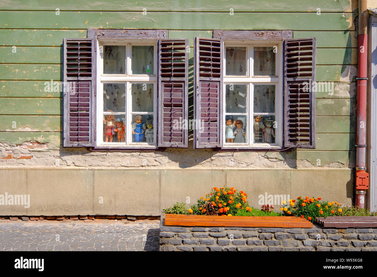 Bündel von Puppen in Windows starrte mit offenem Fensterläden im Zustand der leichten Verfall Stockfoto