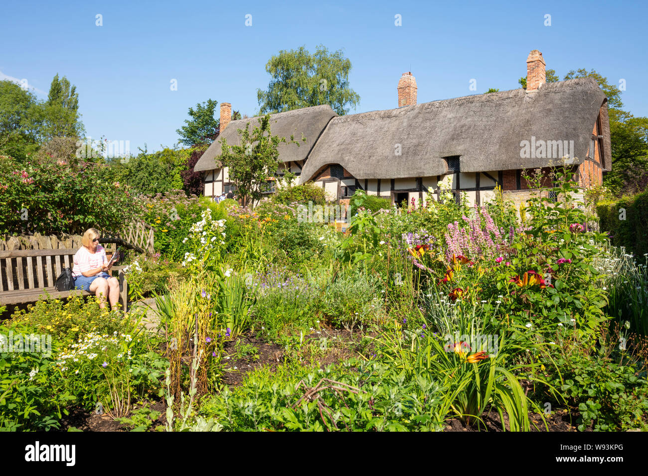 Anne Hathaway Cottage ein strohgedecktes Cottage in einem Cottage Garten mit einer Frau, die auf einer Bank Shottery in der Nähe von Stratford upon Avon Warwickshire England GB saß Stockfoto