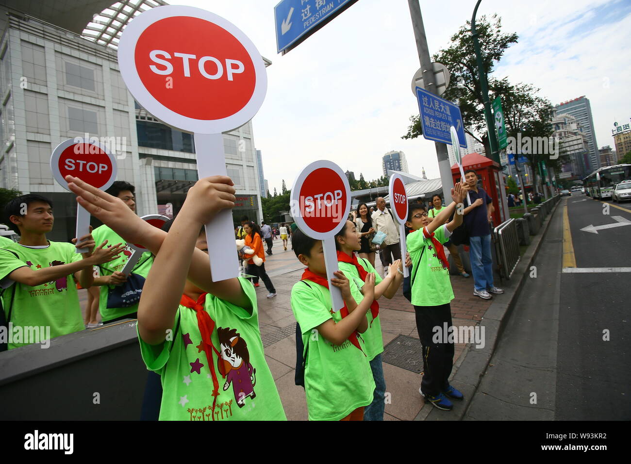 Chinesischen Probanden halten Stoppschilder gegen jaywalking an einem roten Licht auf einer Straße in Shanghai, China, 2. Juni 2013. Chinesische Beamte sind Risse tun Stockfoto