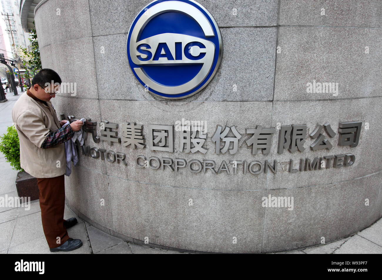 ---- Ein chinesischer Arbeiter Stäube aus dem Logo der SAIC Motor Corporation Limited am Tor der Hauptsitz der SAIC Motor in Shanghai, China, 8 Apri Stockfoto