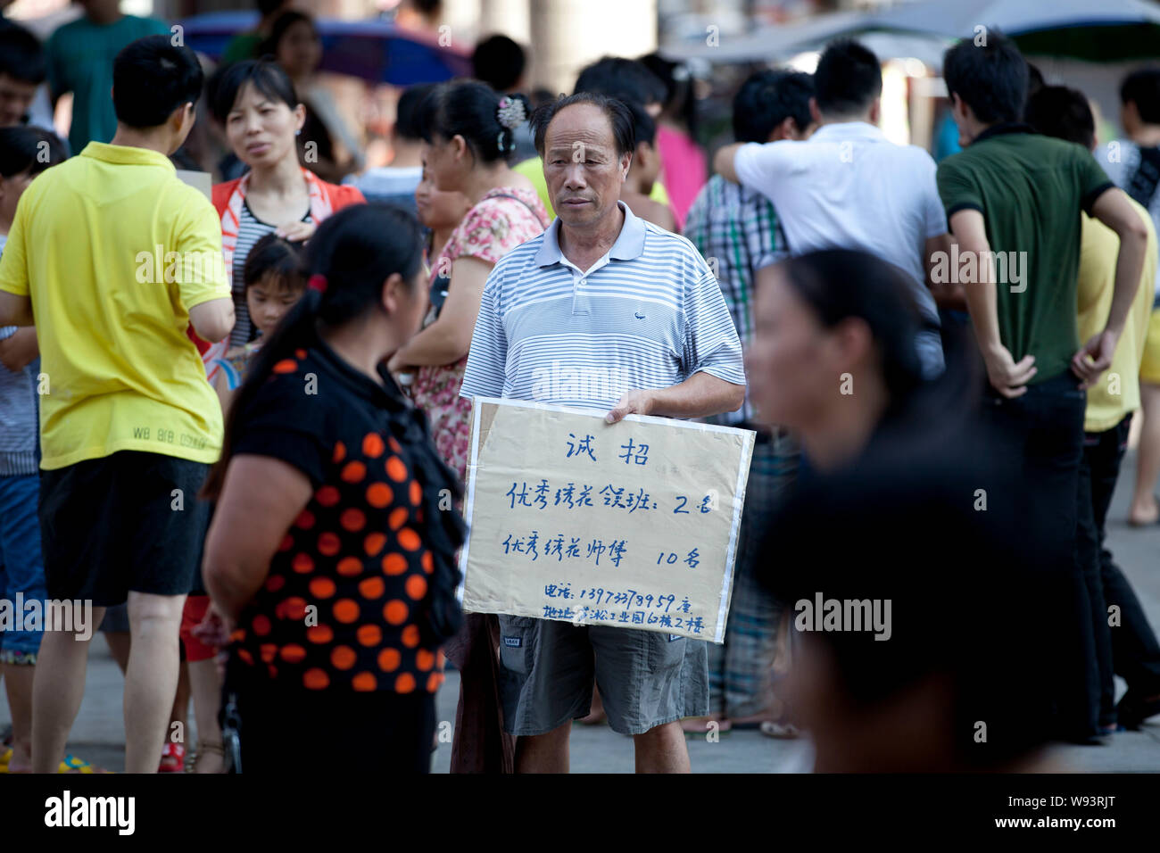 Eine chinesische Recruiter hält ein Plakat, Anzeigen von Informationen der Arbeitsplätze durch eine Fabrik in einem Arbeitsmarkt, in Zhuzhou Stadt angeboten, Zentrale China Provinz Hunan, Stockfoto