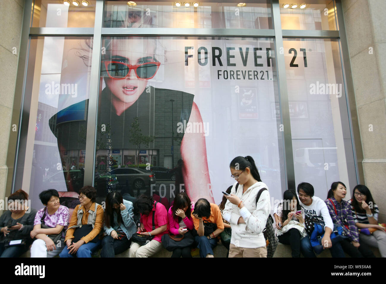 ---- Fußgänger sitzen vor einem Fashion Store von FOREVER21 in Shanghai, China, 29. September 2012. Einige Chargen von Kleidung von Welten leadin Stockfoto