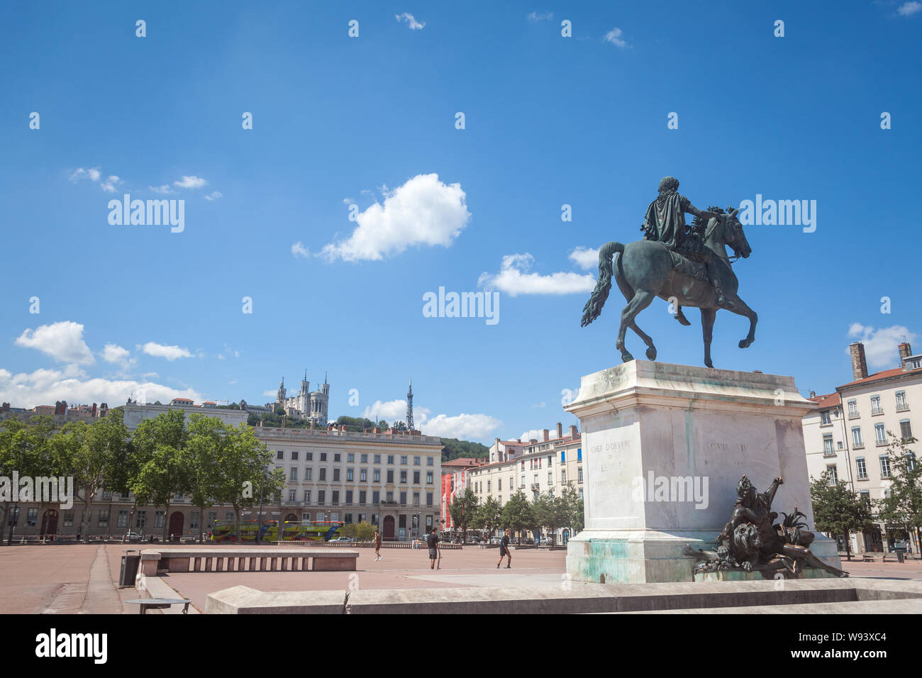 LYON, Frankreich - 14 Juli, 2019: Roi Louis XIV Statue auf den Place Bellecour Square, in der Innenstadt von Lyon, mit der Basilika Notre Dame De Fourviere Kirche Stockfoto