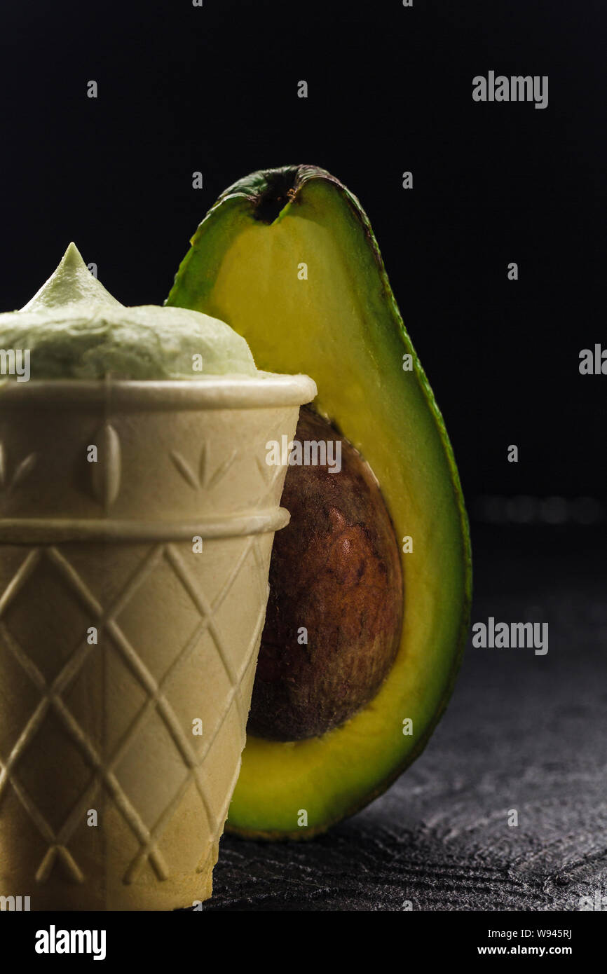 Avocado Schnitt mit dem Knochen und Eis in der Waffel Schale auf einem  dunklen Hintergrund closeup mit Copyspace. Das Konzept der gesundes Essen  und Junk Food Stockfotografie - Alamy