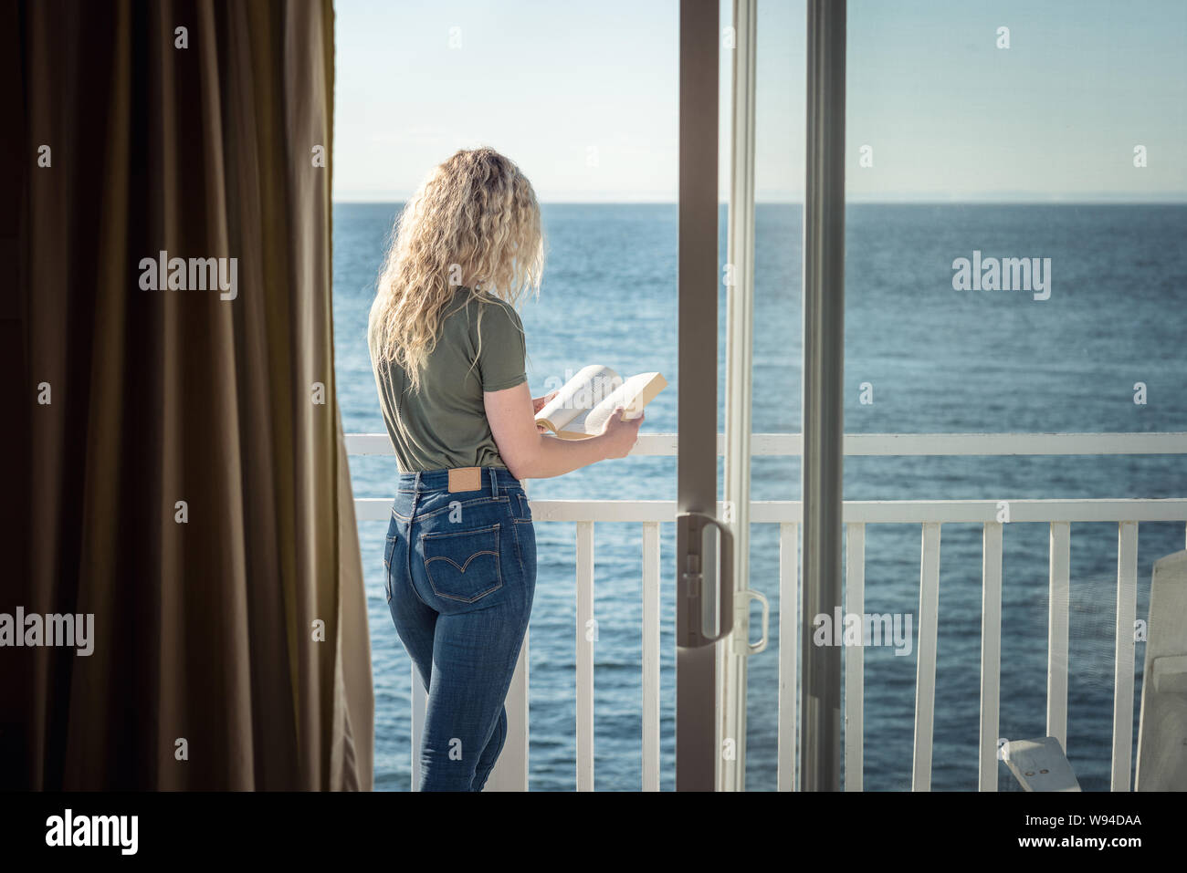 Blonde Frau mit einem Buch vor dem Meer Stockfoto