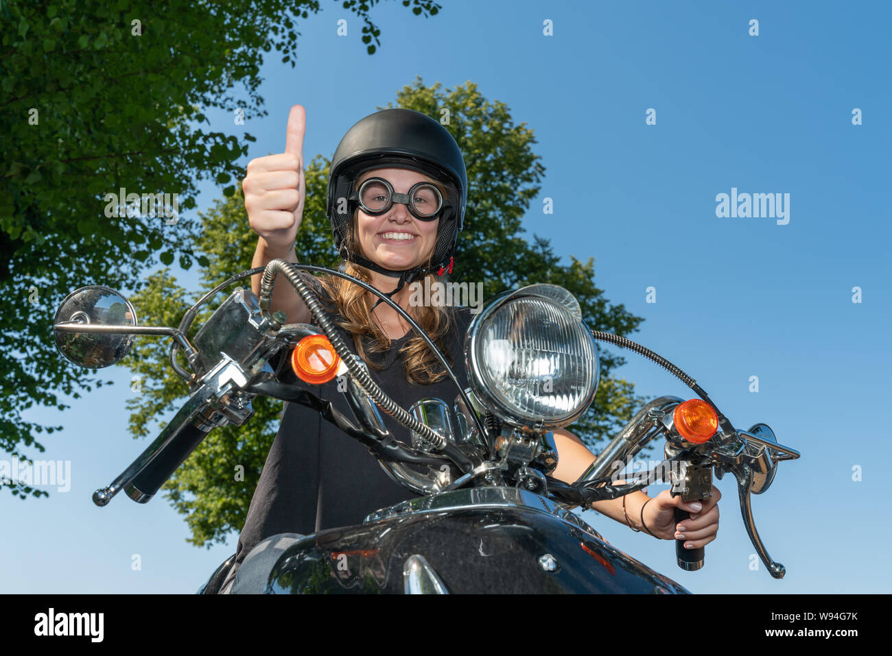 Oung Frau treibt ein Roller und hält den Daumen hoch Stockfoto