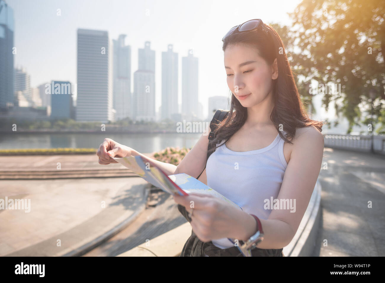 Schöne asiatische Solo touristische Frau suchen an der Karte auf der Suche nach Touristen Besichtigungen vor Ort. Ferienhäuser Reisen im Sommer. Stockfoto