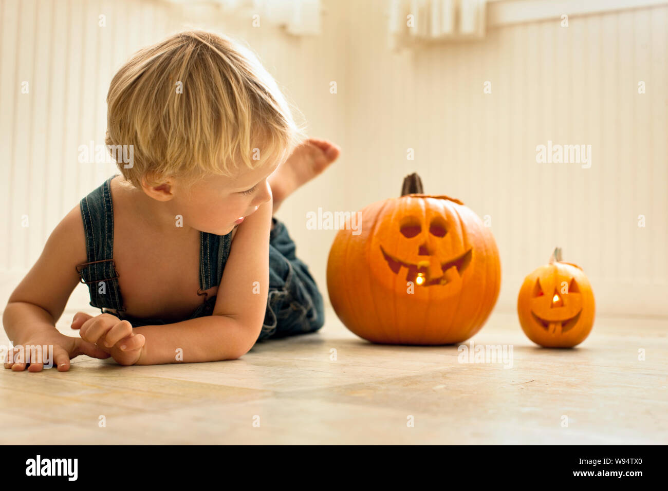 Junge Junge auf einem Stockwerk und Blick auf einen großen Jack O'Lantern und einen kleinen Jack O'Lantern Stockfoto