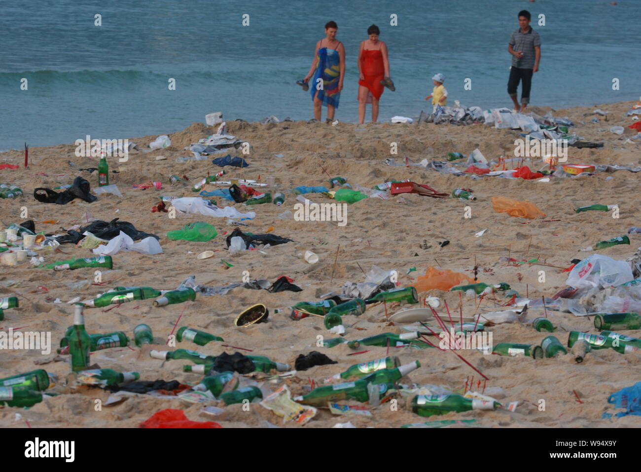 Touristen zu Fuß am Strand mit Müll von anderen an der East China Sea scenic Spot in Sanya city Links, South China Hainan Provinz bedeckt, 1. Oktober Stockfoto