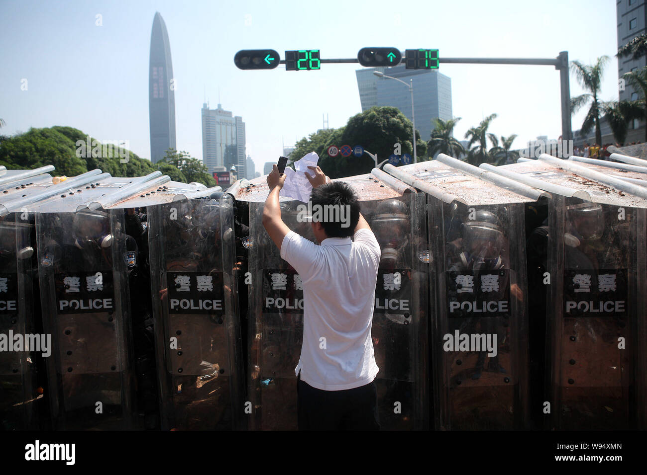 Ein chinesischer Demonstrant hält Papier mit Protest Parolen vor Polizisten hinter Abschirmungen während eines anti-Japan protest Parade in der Stadt Shenzhen Stockfoto