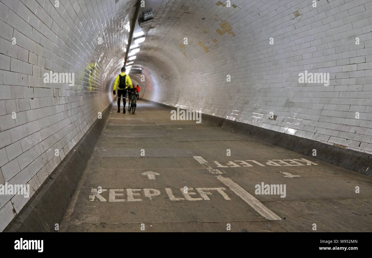 Radfahrer tragen gelbe Jacke gehen mit seinem Fahrrad in Greenwich foot Tunnel unter der Themse mehr verwischt Fußgänger im Hintergrund, Halten Stockfoto
