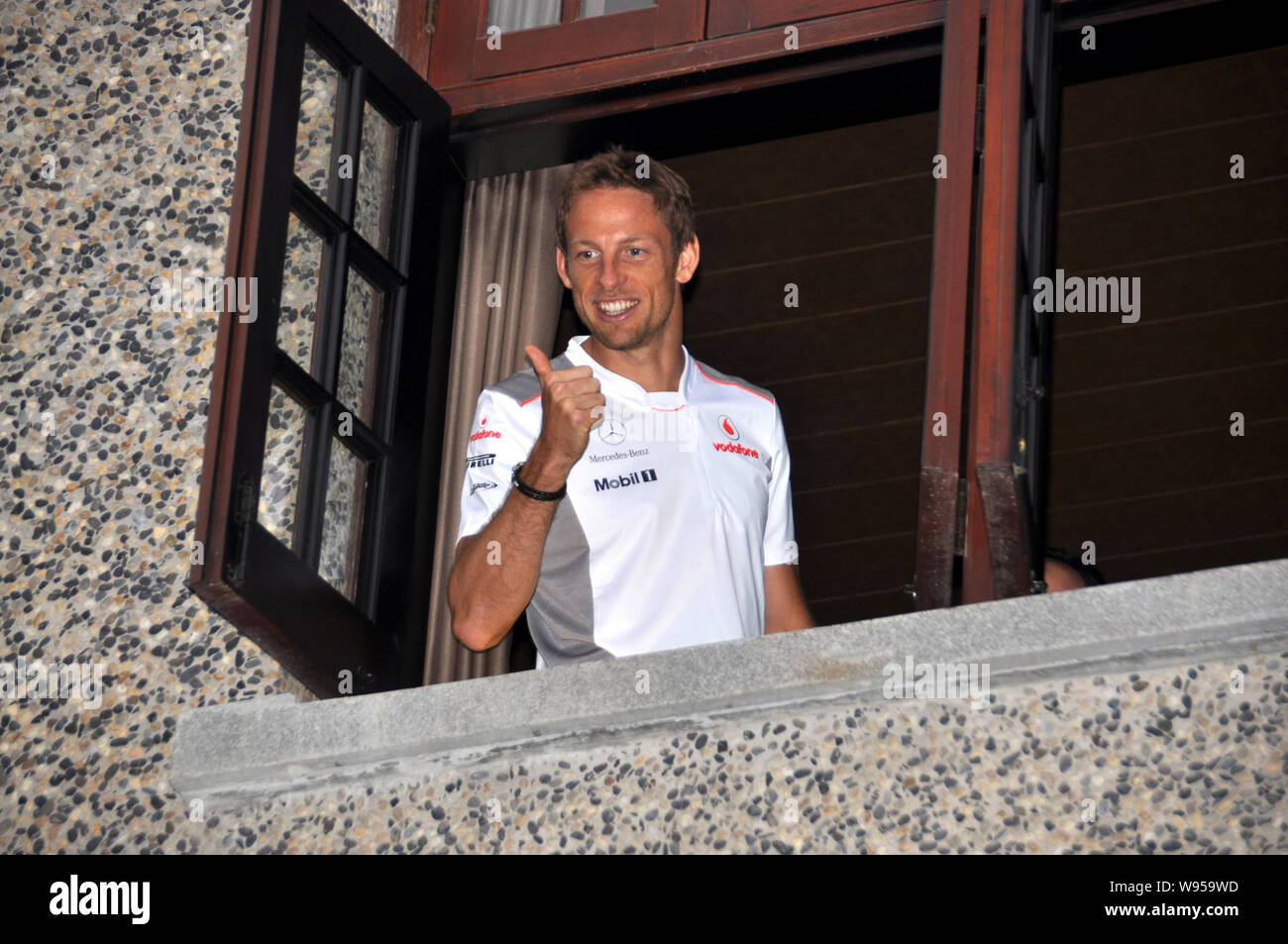 Britische F1 Fahrer Jenson Button von McLaren-Mercedes Team stellt durch das Fenster eines privaten Apartments während einer Werbeveranstaltung in Shanghai, China, Stockfoto