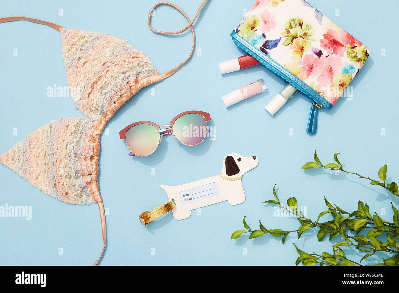 Junge Frau Strand Urlaub Mode und Beauty Produkte und Zubehör flach auf blauem Hintergrund Stockfoto