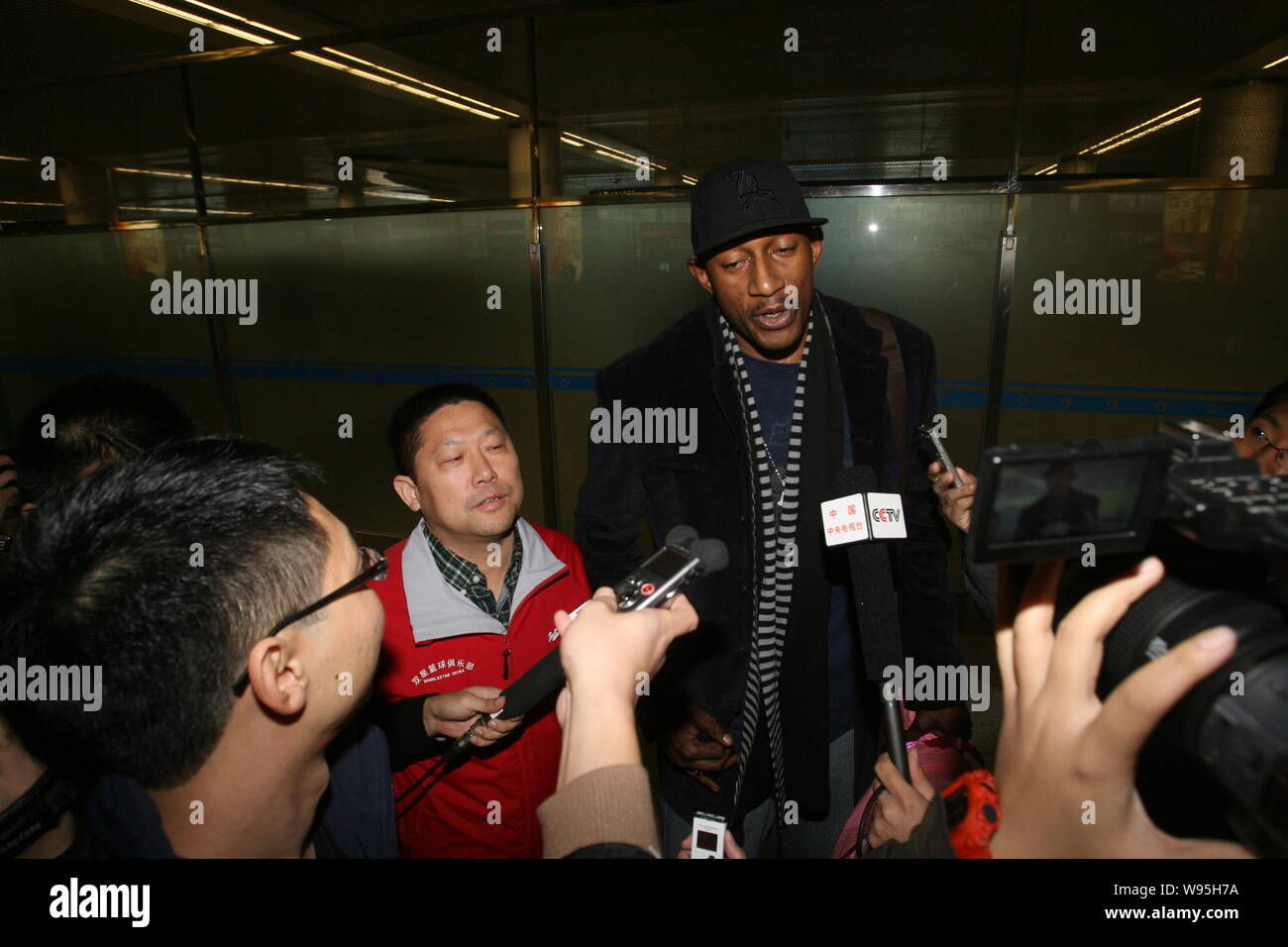 Ehemaliger NBA Spieler K. Mbenga interviewt wird, als er im Qingdao Liuting International Airport in Qingdao Stadt ankommt, East China Provinz Shandong, 1. Stockfoto