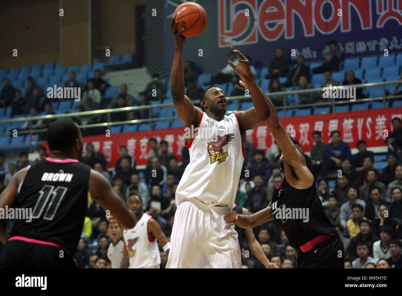 K. Mbenga der Qingdao Adler, oben, springt gegen die amerikanische All-Stars während einer freundlich Basketball Match in Dongying Stadt zu schießen, Ostchina Stockfoto