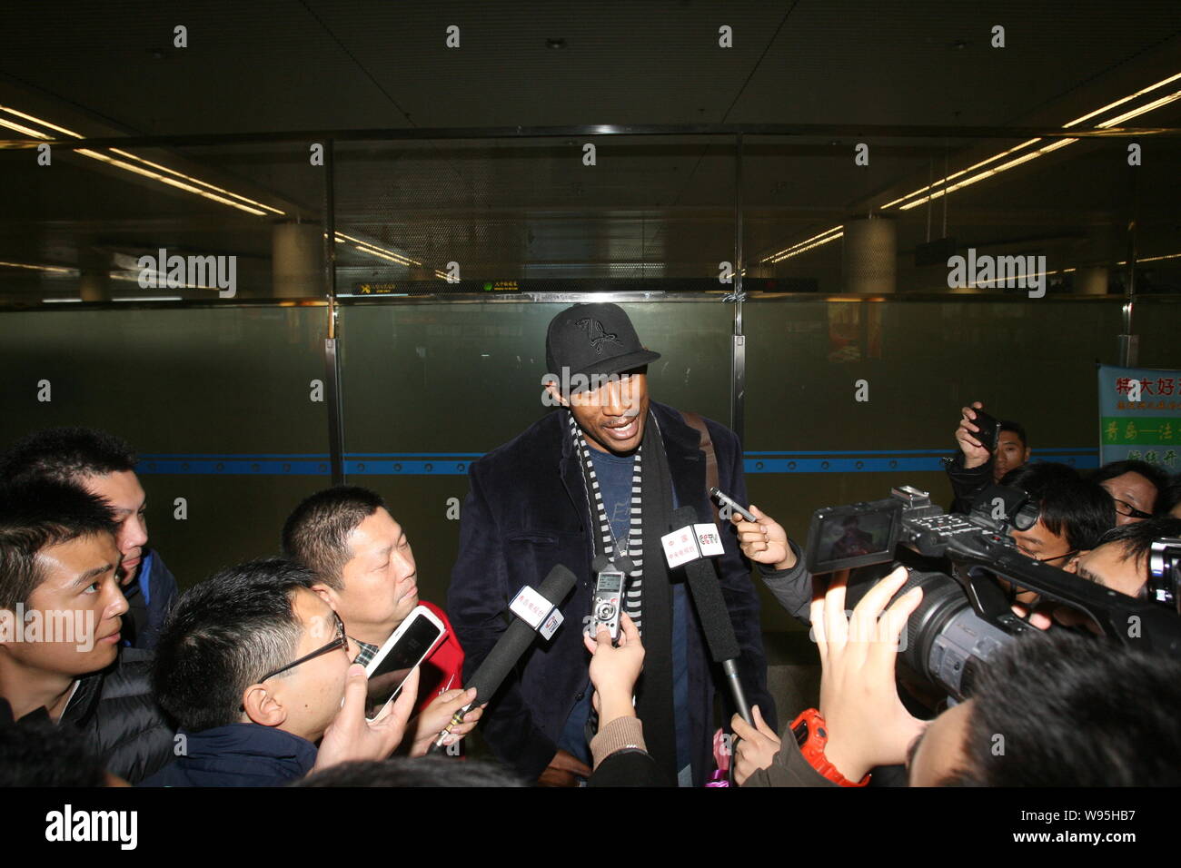 Ehemaliger NBA Spieler K. Mbenga interviewt wird, als er im Qingdao Liuting International Airport in Qingdao Stadt ankommt, East China Provinz Shandong, 1. Stockfoto