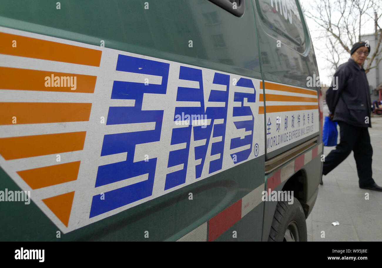 Ein Fußgänger geht hinter einem van mit einem Logo von EMS, eine weltweite  Express Mail Service von China Post Express & Logistics, in Qingdao, e  Stockfotografie - Alamy