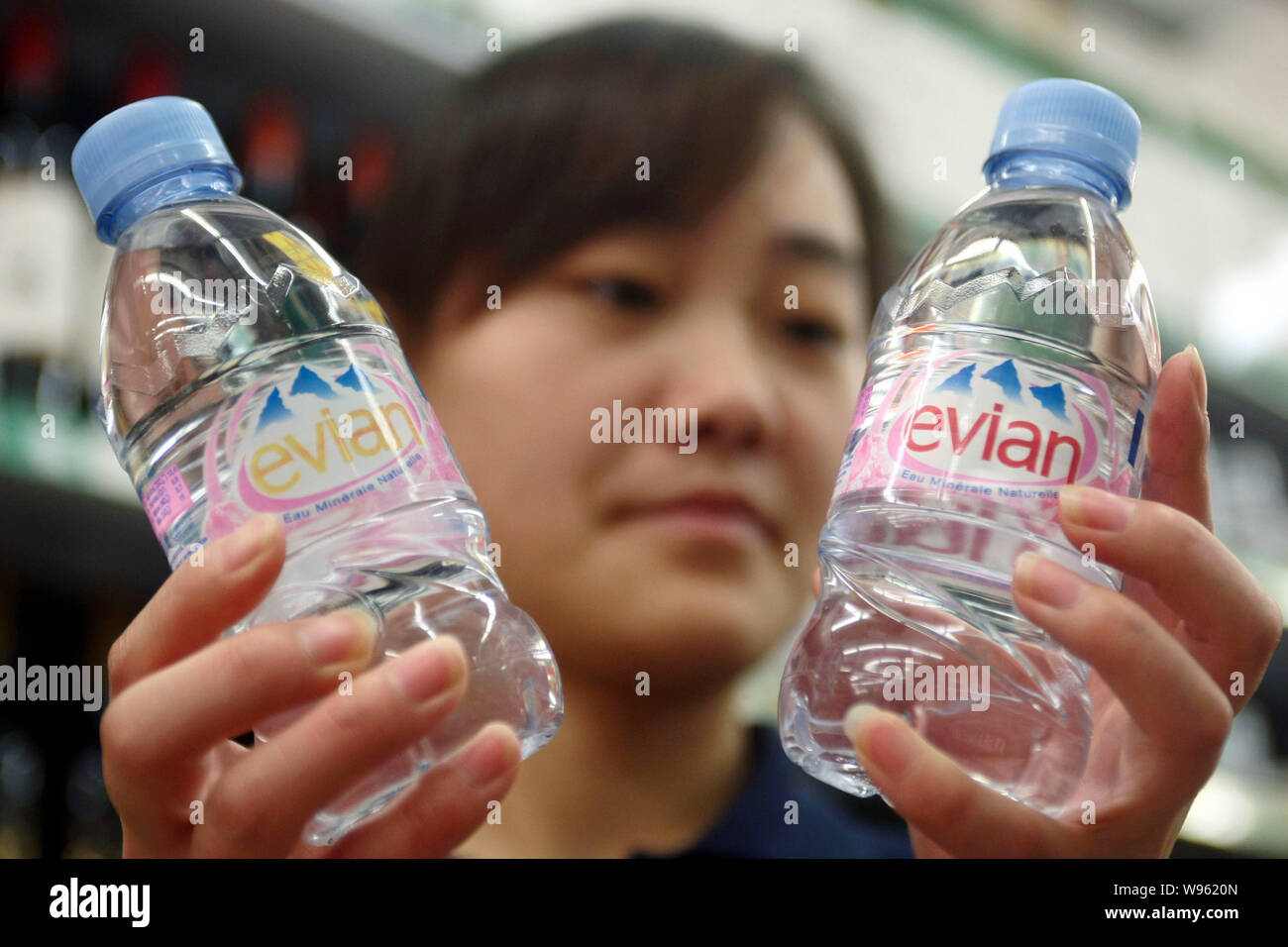 ---- Ein chinesischer Mitarbeiter prüft Flaschen Evian Mineralwasser in einem Supermarkt in Shanghai, China, 17. November 2011. Eine berühmte Marke des Französischen Stockfoto