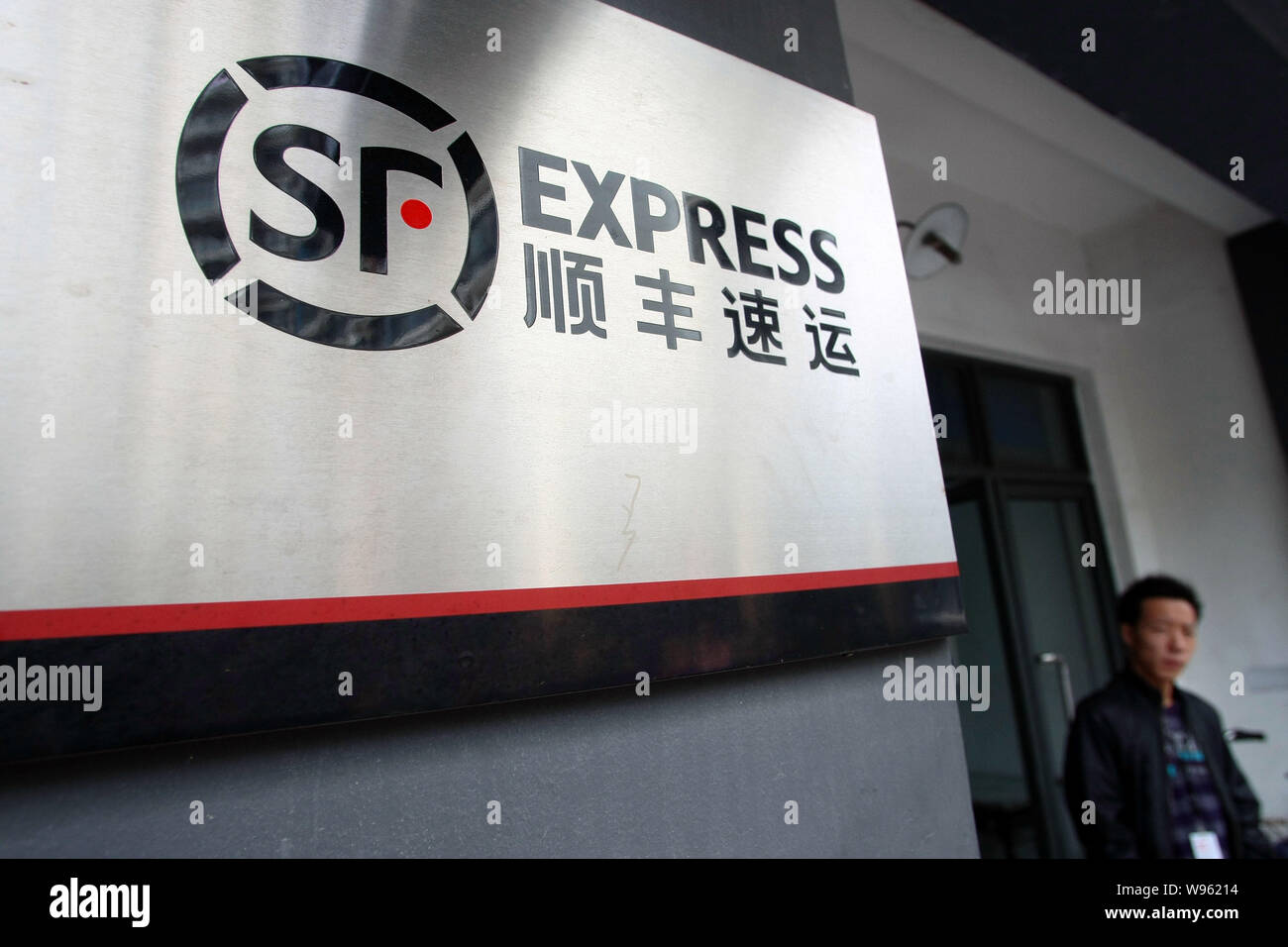 ---- Ein Bürger steht außerhalb einer Niederlassung von Shunfeng Express in Shanghai, China, 10. Oktober 2011. China plant ein echter Name System für e zu implementieren Stockfoto