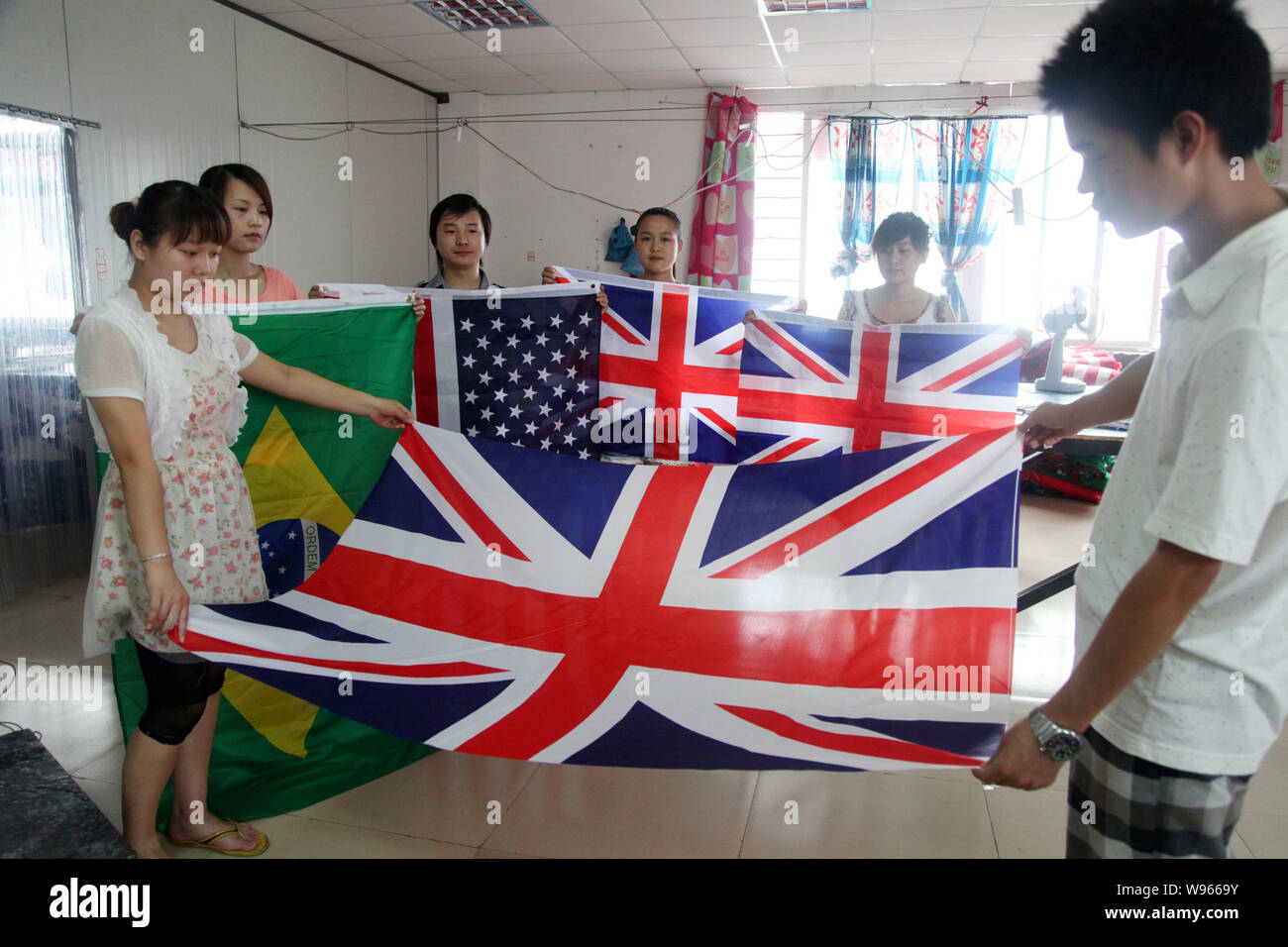 Chinesische Arbeiter Wurfgeschoss nationale Flaggen der USA, Großbritannien und Brasilien im Werk Shaoxing Germanic Textile Co., Ltd. in Shanghai City, East China Zhejia Stockfoto