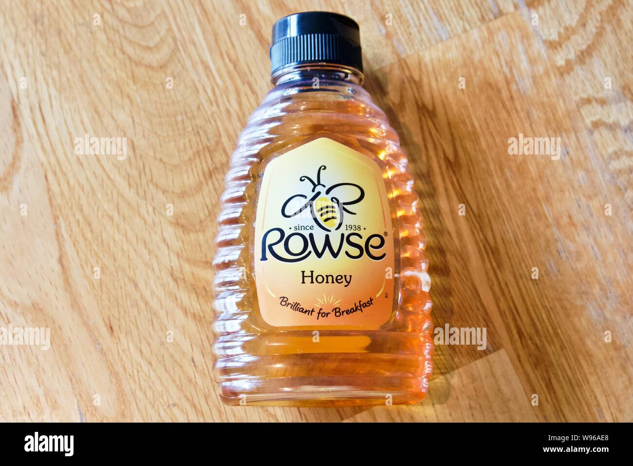 Rowse Honig in einem squeezy Flasche auf einem hölzernen Hintergrund Stockfoto