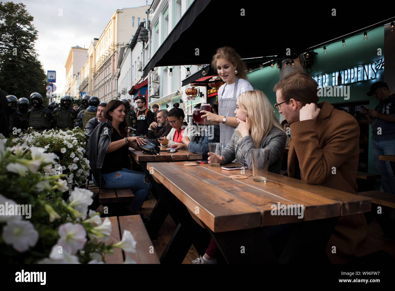 Moskau, Russland - 10 August, 2019, Besucher des Cafe weiter zu essen, während die Polizei die Menschen von der Straße in der Nähe der U-Bahn Stockfoto