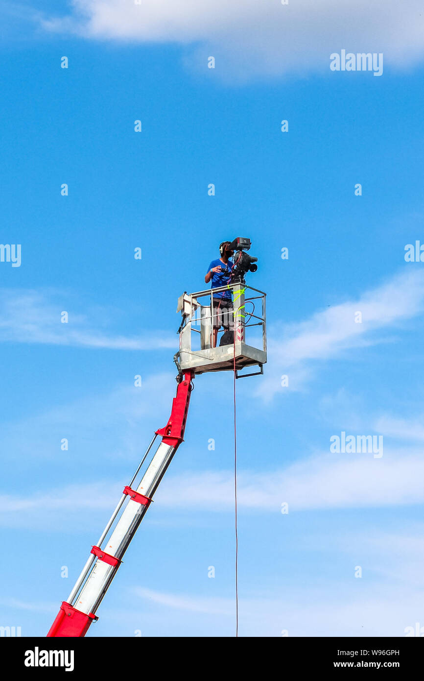 Kameramann Aufnahme auf eine mobile Plattform hoch über dem Boden. Himmel und Wolken im Hintergrund. Film- und Videoproduktion. Media professional Jo Stockfoto