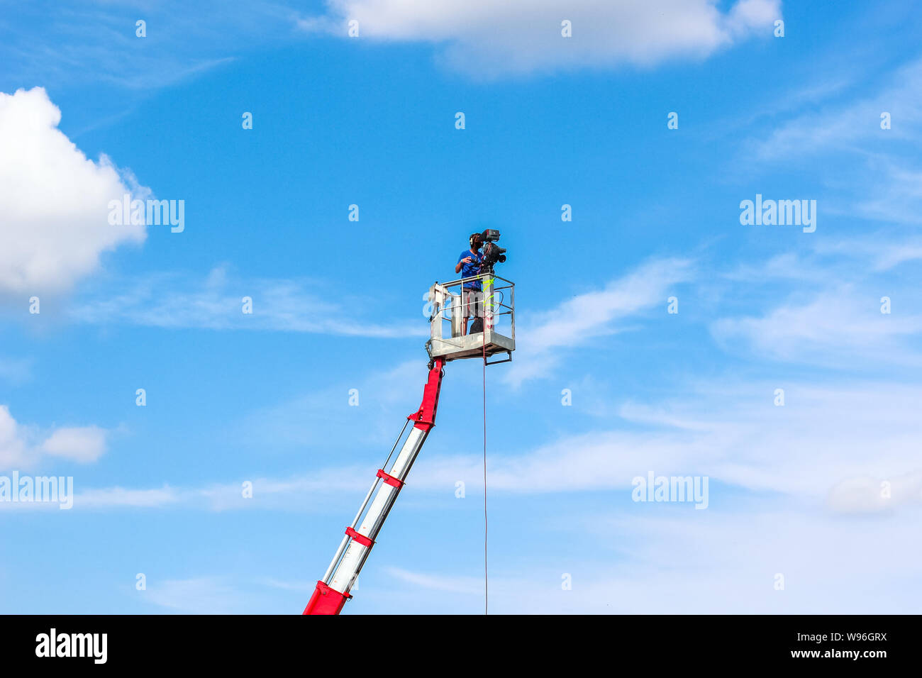 Kameramann Aufnahme auf eine mobile Plattform hoch über dem Boden. Himmel und Wolken im Hintergrund. Film- und Videoproduktion. Media professional Jo Stockfoto