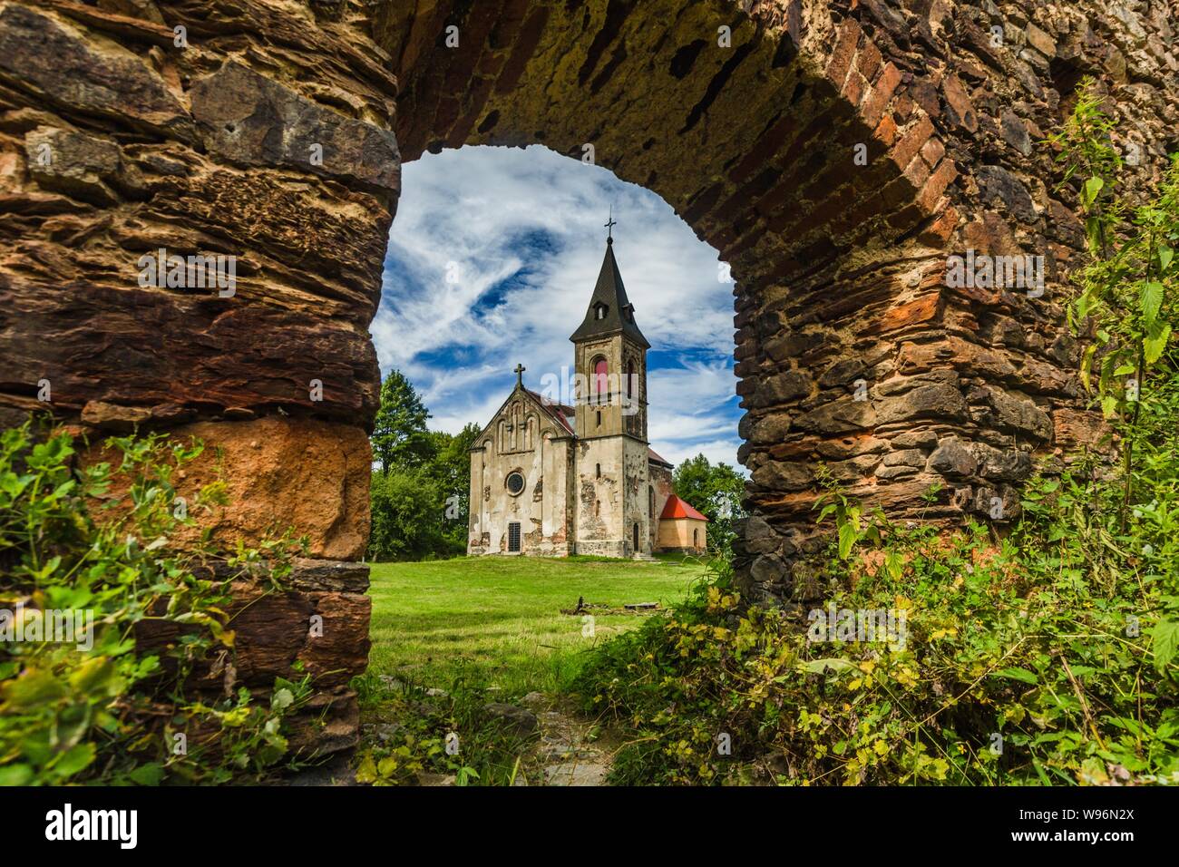 Krasikov, Kokasice/Tschechische Republik - 9. August 2019: Blick auf die alte Kirche der Maria Magdalena über eine Tür in eine Mauer aus Stein von Svamberk schloss. Stockfoto