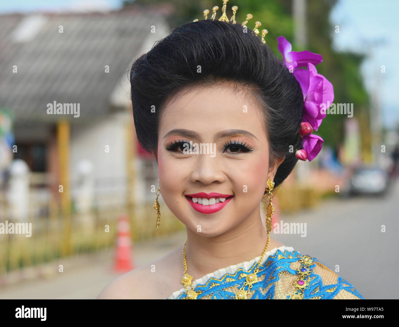 Gekleidet - sich hübsche Thai Mädchen mit Blumen im Haar nimmt Teil an der Geschichte des Dorfes Lanna street parade und Lächeln für die Kamera. Stockfoto