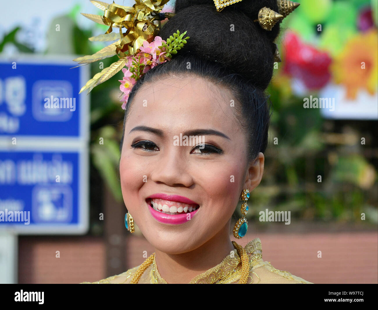 Kostümierte Thai Mädchen mit Blumen im Haar im historischen Teil des Dorfes Lanna street parade und Lächeln für die Kamera nimmt. Stockfoto