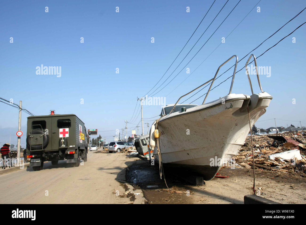 Eine medizinische Fahrzeug passiert einen Yacht und die Trümmer des tsunami Verwüstungen durch den 9,0-Erdbeben in Sendai, Japan, 13. März 2011 verursacht. Stockfoto