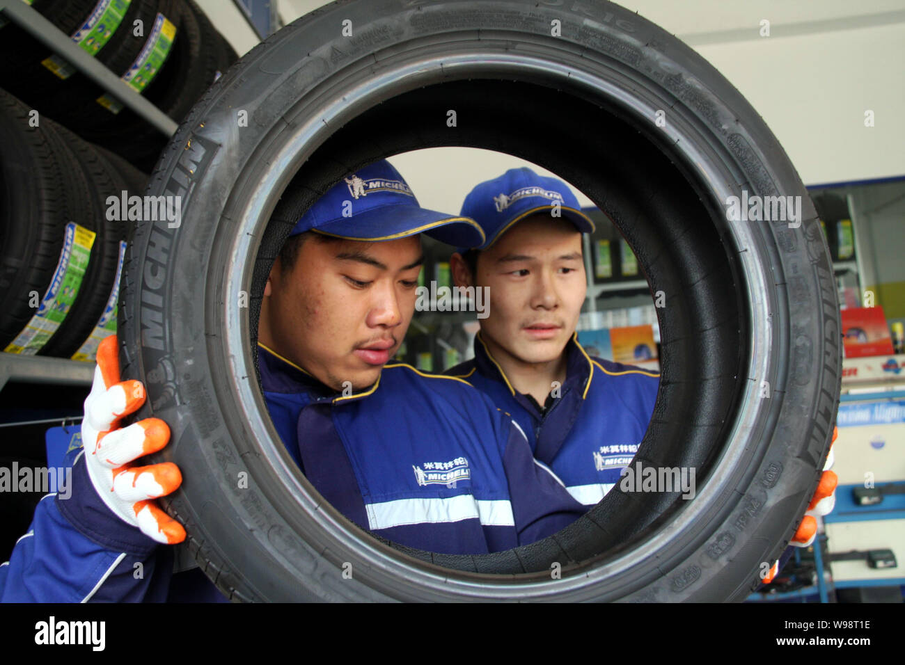 ---- Zwei chinesische Arbeiter prüfen Michelin Reifen an einem Auto Repair Station in Nantong City, East China Jiangsu Provinz, 25. November 2010. Michelin & Stockfoto