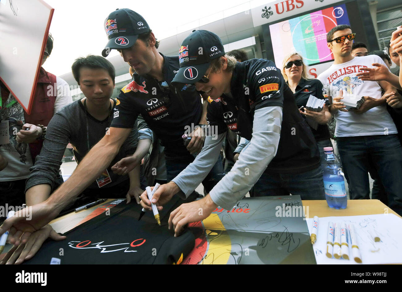 Die deutschen F1 Fahrer Sebastian Vettel, vorne rechts, und seinen australischen Teamkollegen Mark Webber von Red Bull Racing Team anmelden Poster an der Shanghai Inter Stockfoto