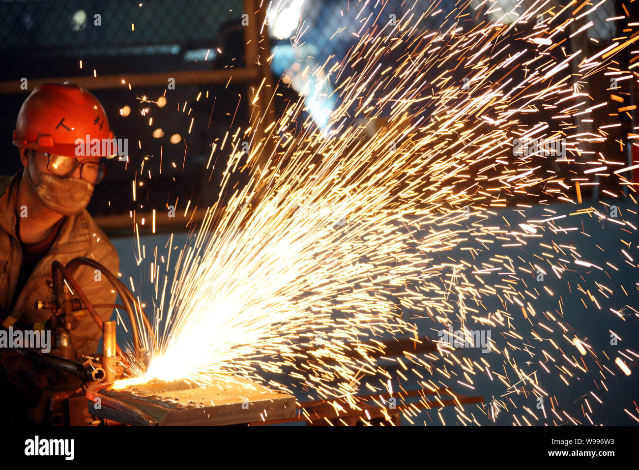 ---- Ein chinesischer Arbeiter führt Schweißarbeiten an einem stahlerzeugnisse Anlage in Stadt Huaibei, East China Provinz Anhui, 28. Juli 2011. China econom Stockfoto