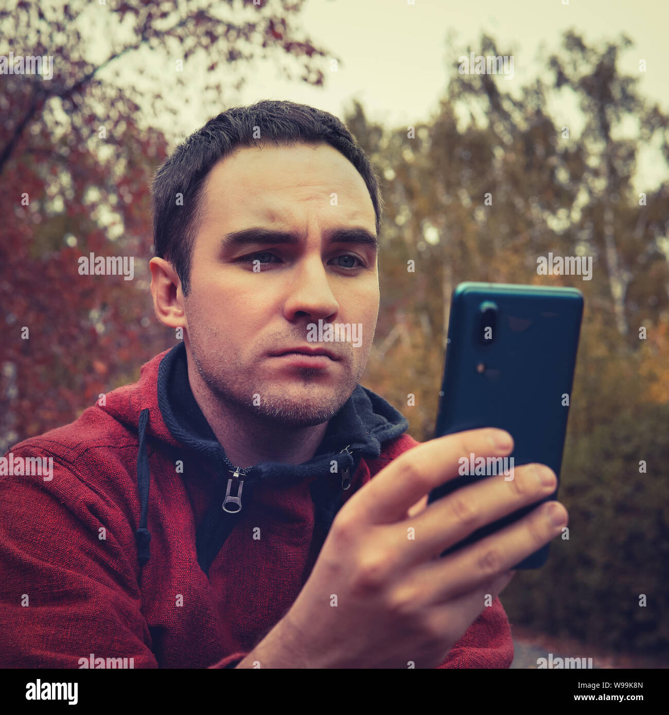 Kerl mit Smartphone outdoor, Outdoor Portrait von junge fröhliche Mann Simsen eine SMS-Nachricht an sozialen Netzwerken, Technologie, Konzept, Unmut Stockfoto