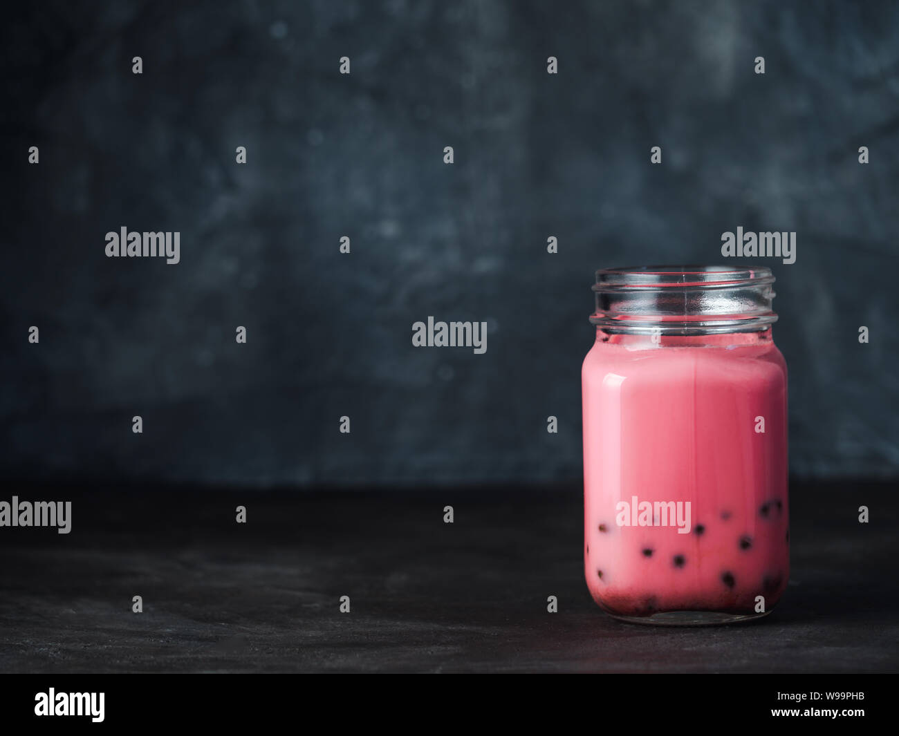 Hausgemachte Milch Bubble Tee mit Tapioka Perlen Kugeln. Beliebte Taiwan Bubble Tee in Glas-Einmachglas mit Platz für Text kopieren. Pink Bubble Tee auf dunklem Hintergrund. Stockfoto
