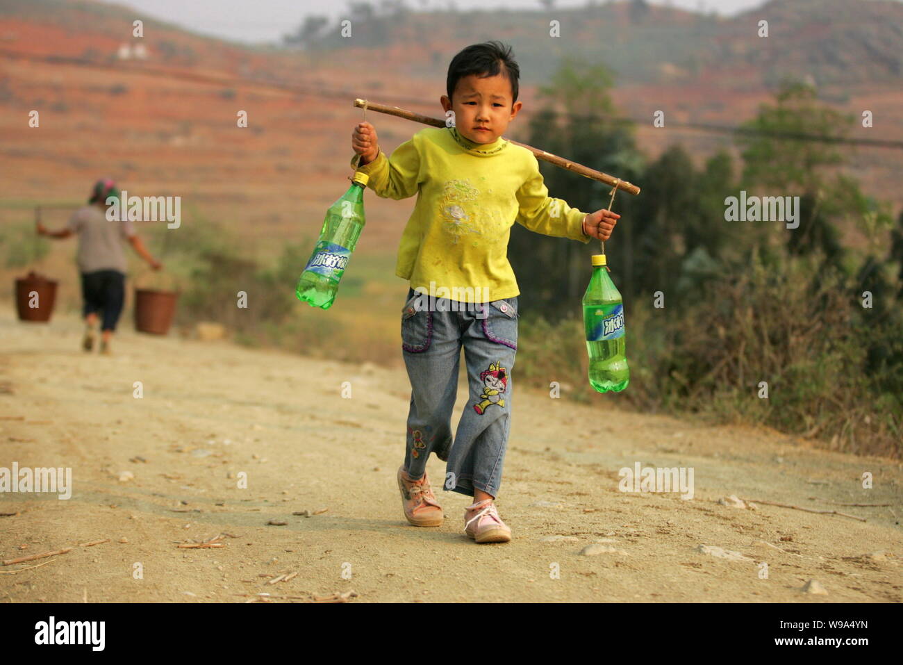 Ein chinesisches Kind trägt zwei Flaschen Wasser auf seinem Weg nach Hause während einer schweren Dürre in Dashiqiao Dorf, Shilin County, Kunming City, im Südwesten von China Stockfoto