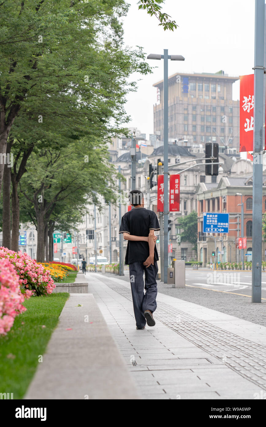 Ein einziger Mann geht durch die Straßen in Shanghai, China, nahe der berühmten Aussicht auf die Pudong Skyline. Stockfoto