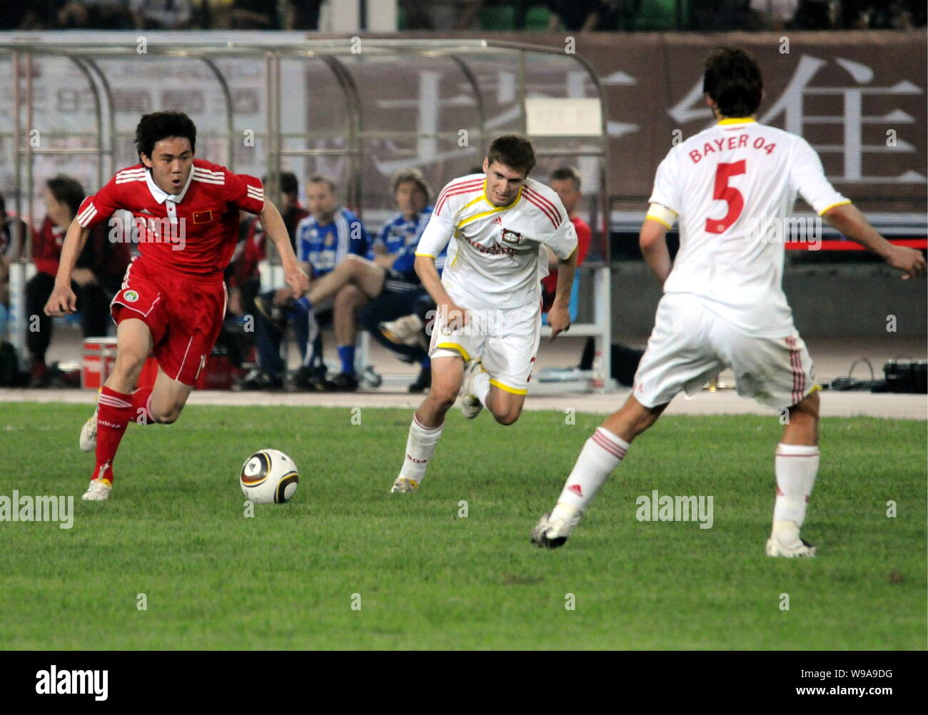 Li Xuepeng, Links, der chinesischen nationalen mens Fußball-Team versucht, durch Daniel Schwaab, in der Mitte zu brechen, und Manuel Friedrich, rechts, von Bayer 04 Lev Stockfoto