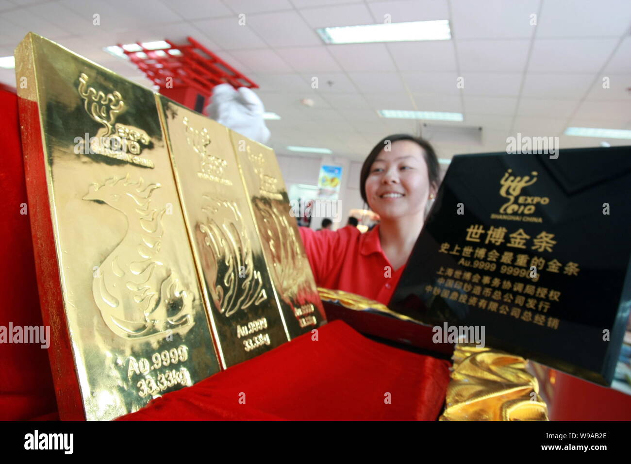 Ein chinesischer Mitarbeiter zeigt drei Shanghai Expo-themed Gold Bars in einer Welt Expo Franchise Store in Shanghai, China, 12. Mai 2010. Die drei reines Gold b Stockfoto