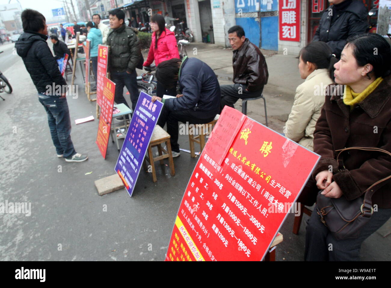 Chinesische Unternehmen Vertreter neben Job Angebote Sitzen für Arbeitsuchende auf einem Arbeitsmarkt, in Nantong City warten, East China Jiangsu Provinz, 25 Fe Stockfoto