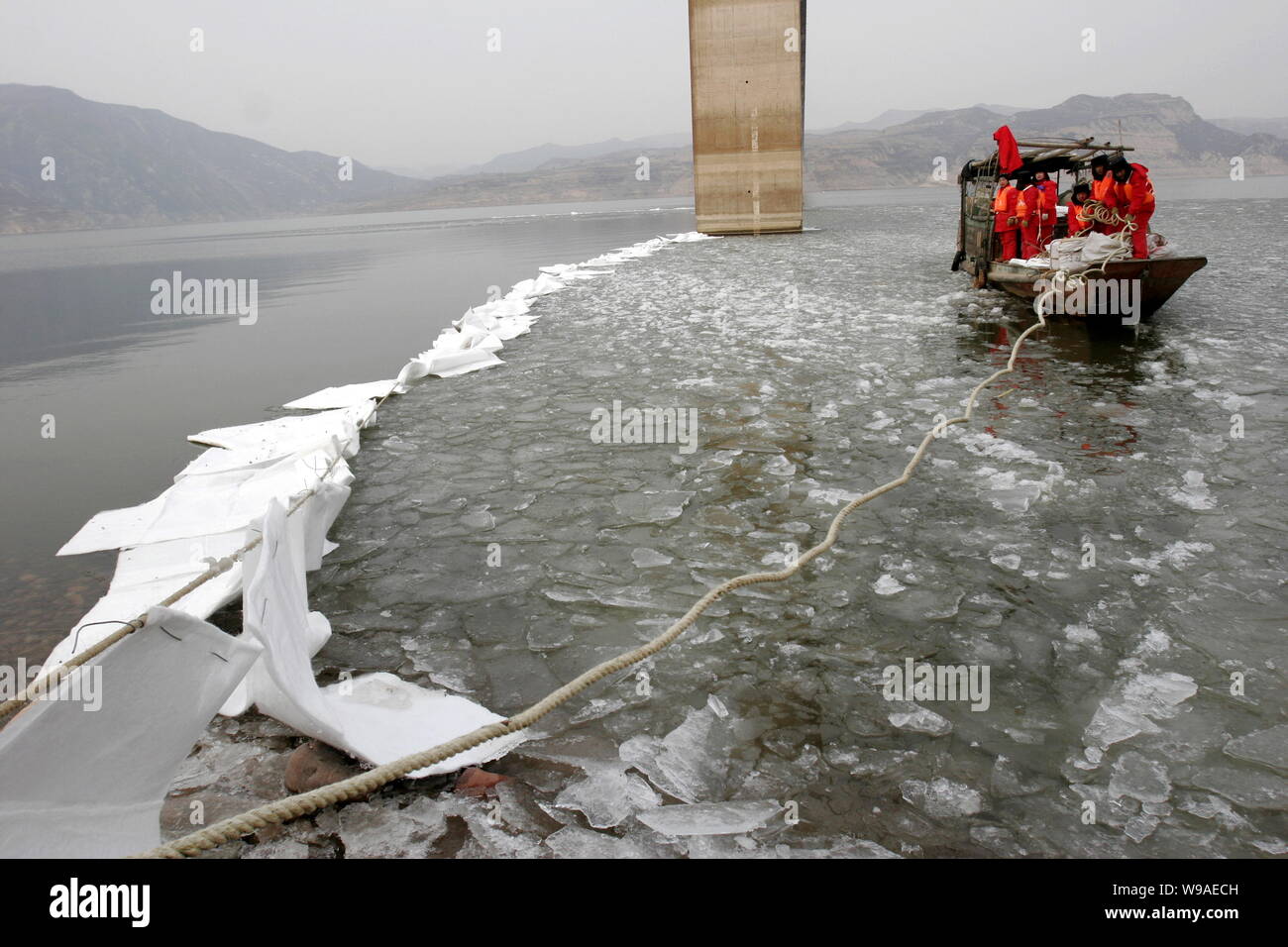 Die chinesischen Arbeiter die eine Barriere mit ölsperren am Gelben Fluss unter dem Nancun Yellow River Bridge Diesel zu stoppen nach einer Ölpest in Mianchi Stockfoto Die chinesischen Arbeiter die eine Barriere mit ölsperren am Gelben Fluss unter dem Nancun Yellow River Bridge Diesel zu stoppen nach einer Ölpest in Mianchi Stockfoto