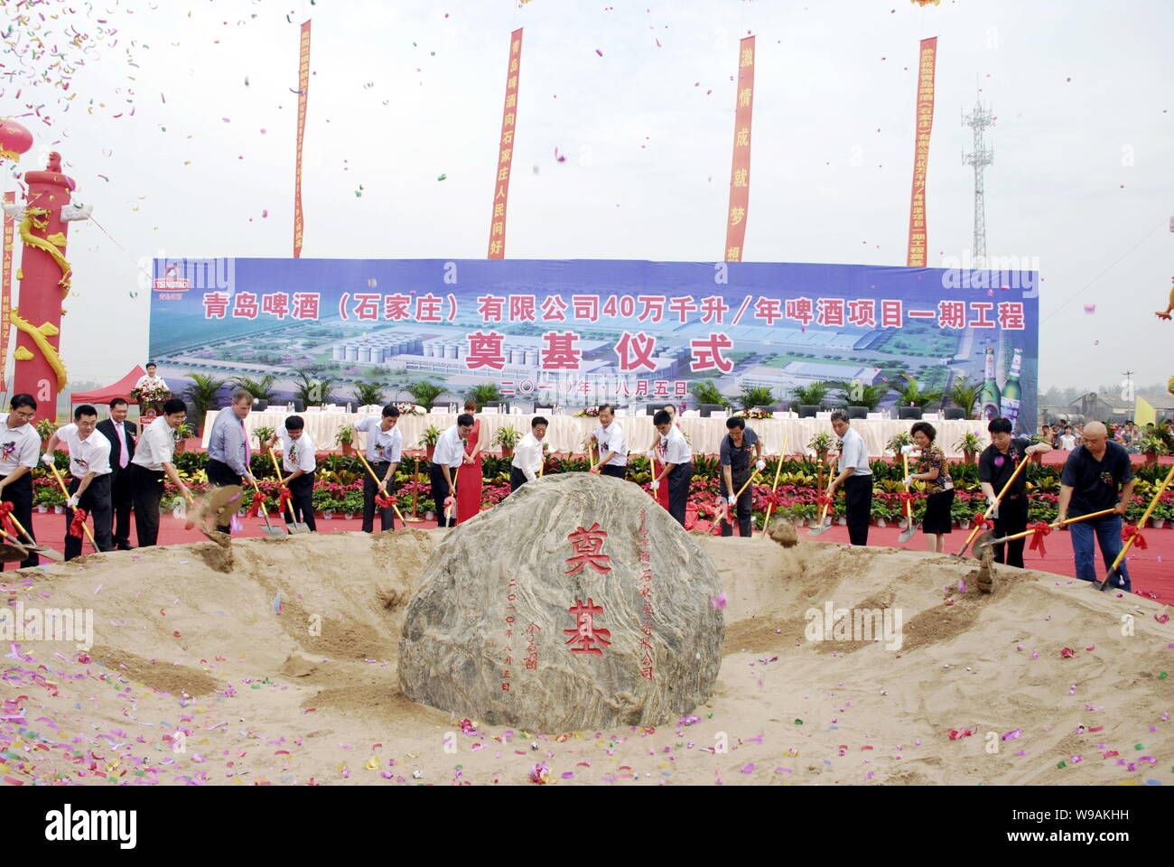 Chinesische Beamte und Manager von Tsingtao Brewery Group Schaufel Sand einen Grundstein in den Spatenstich für die erste Phase zu begraben. Stockfoto